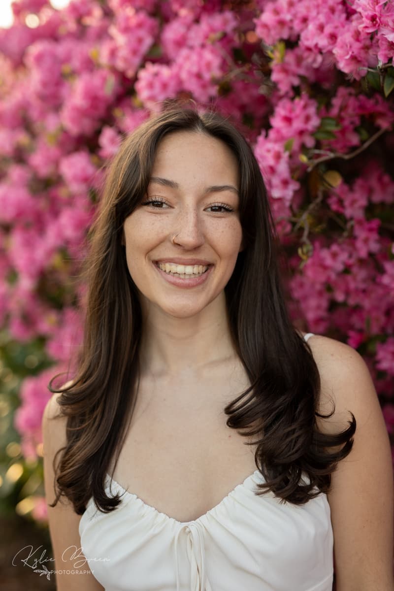 Emily Crain smiling in front of pink flowers